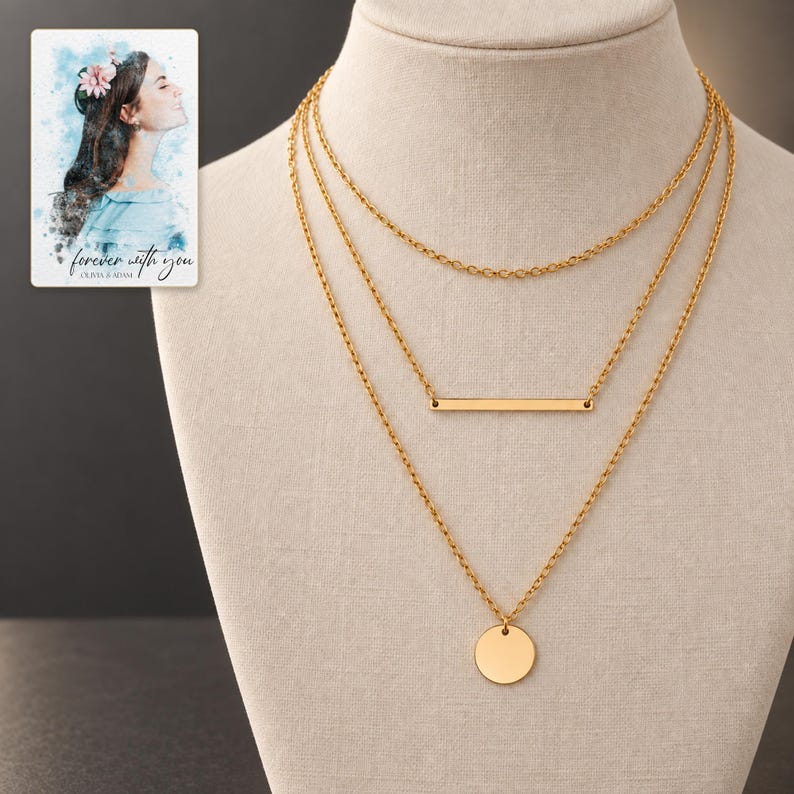 Three-layer gold-tone necklace set on an ivory display against a dark graphite background. A personalized digital greeting card is shown alongside.