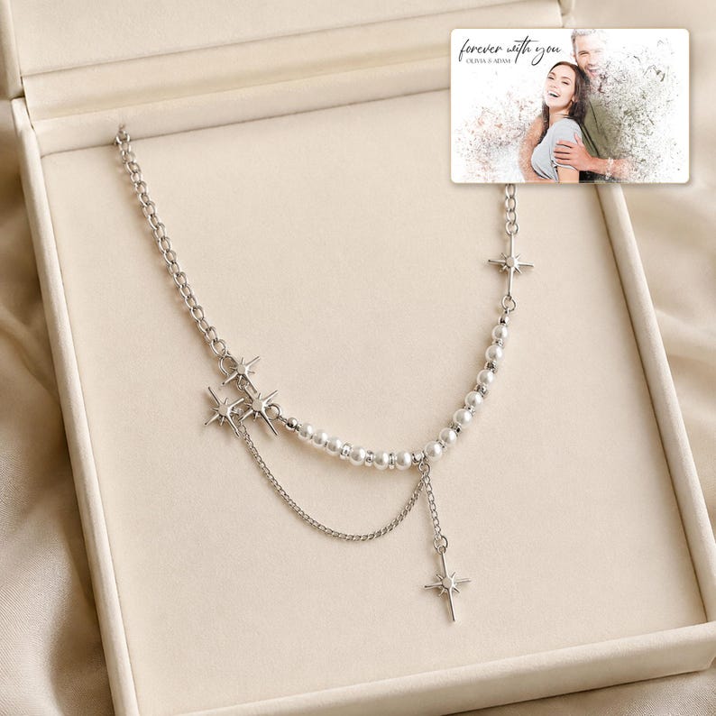 Silver-tone layered necklace with pale beads and pointed star charms, presentation in an open jewelry box. A personalized greeting-card example appears in the corner.