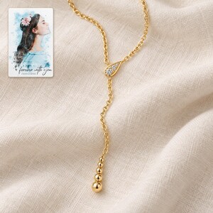 Moissanite Y Necklace, linen flatlay view. A personalized digital greeting card is shown alongside.