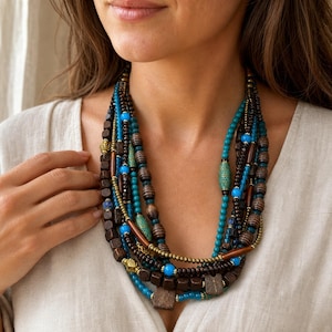 Turquoise blue and dark brown multistrand statement beaded necklace displayed on a jewelry bust with all turquoise, dark wood and antique brass strands visible