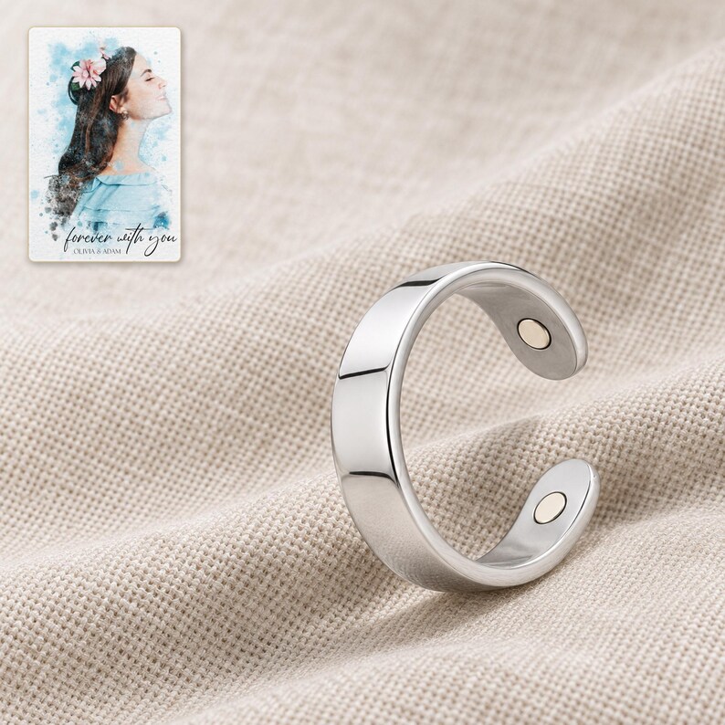 Polished open silver-tone ring resting on folded oatmeal linen with its two inner-tip details facing the camera. A personalized digital greeting card is shown alongside.