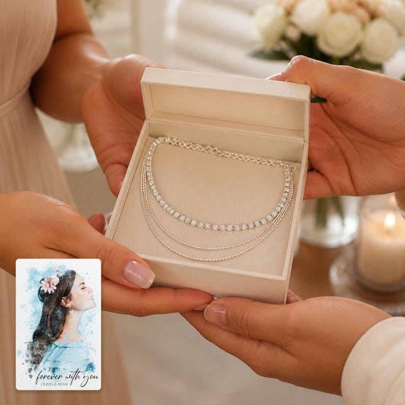 May include: A silver-toned multi-strand necklace featuring a row of clear round stones and two delicate chains inside a cream-coloured gift box, accompanied by a small card with a watercolour illustration of a person and the text "forever with you".
