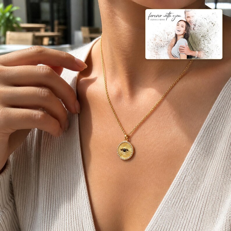Gold-tone necklace with a round sunburst and black eye detail, adult lifestyle view. A personalized greeting-card example appears in the corner.
