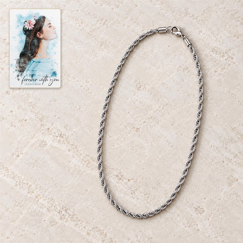 Full silver-tone twisted rope necklace arranged in a close oval on pale stone style with its lobster clasp visible. A personalized digital greeting card is shown alongside.