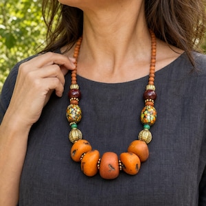 Three-piece handmade necklace set featuring orange and brown beaded necklace, orange and brown beaded necklace and orange and brown beaded necklace, displayed together to show the coordinated colors and beadwork