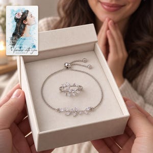 An adult woman receiving an open ivory jewelry box with the coordinating leaf bracelet and ring visible. A personalized digital greeting card is shown alongside.