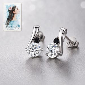 Polished sterling silver and zircon stud earrings styled with sophisticated evening lighting and fabric.