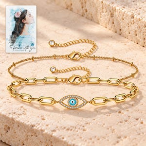Gold Tone Evil Eye Bracelet Duo shown in a close macro view highlighting the visible, texture and construction details. A personalized digital greeting card is shown alongside.