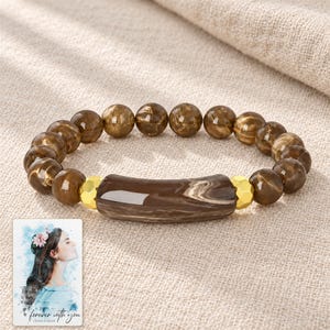 Cocoa Swirl Bar Bracelet arranged on soft ivory linen in a refined neutral flat lay. A personalized digital greeting card is shown alongside.