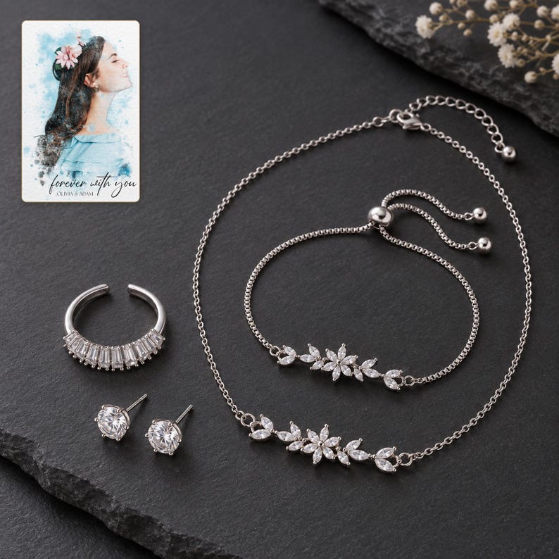 Silver-tone floral jewelry set with clear stone style displayed against charcoal slate. A personalized digital greeting card is shown alongside.