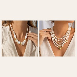 May include: Two necklaces featuring white pearls. The first necklace has varied pearl shapes and gold-toned spacers. The second necklace is a multi-strand design composed of small white pearls, gold-toned beads, and a central gold-toned heart charm.