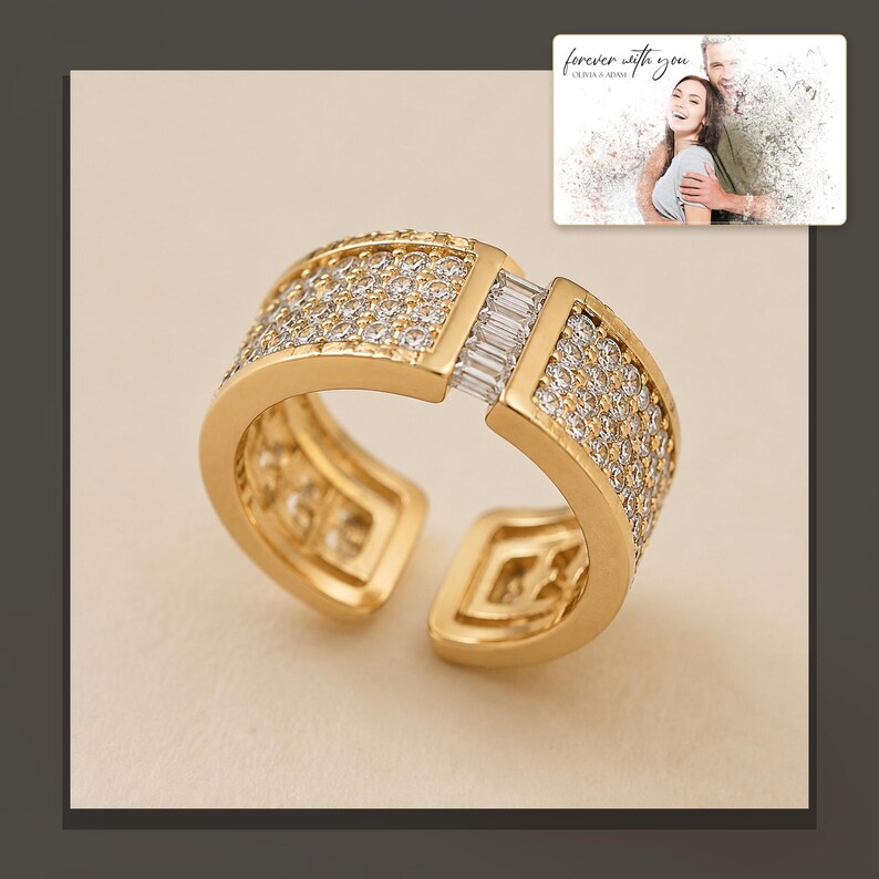 Gold-tone open ring with rows of clear accents, dark-bordered product view. A personalized greeting-card example appears in the corner.