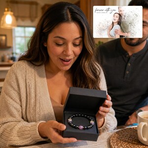 May include: A black gift box containing a beaded bracelet with dark grey spherical beads, interspersed with smaller metallic spacers and three translucent purple beads. The box is presented alongside a card featuring a couple and the text forever with you.
