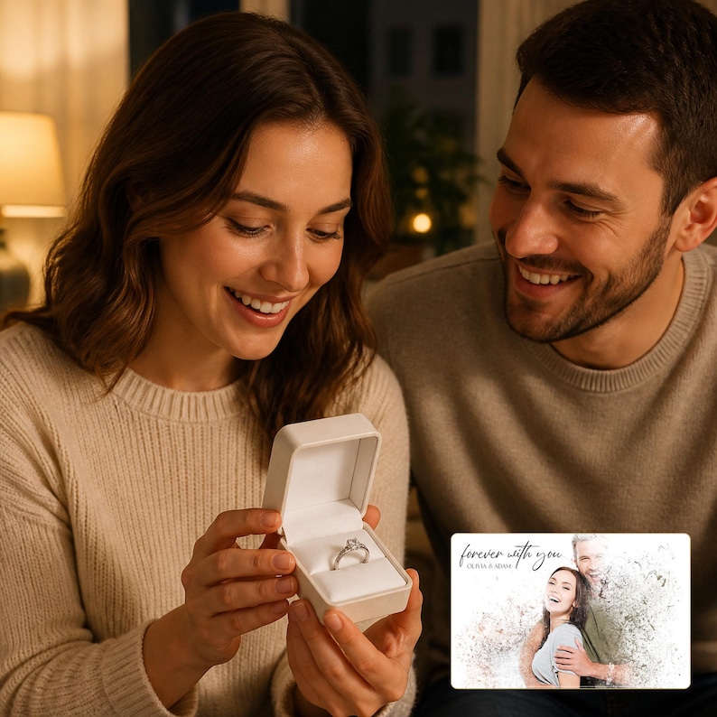 May include: A silver-toned ring with a central gemstone set in a white square jewelry box. Beside the box is a rectangular card featuring a printed photograph of a couple with the text "forever with you" and "OLIVIA & ADAM" in script.