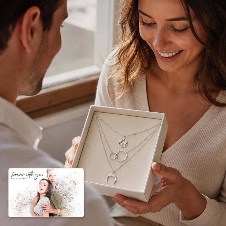 May include: A silver-toned multi-strand necklace set featuring three distinct pendants: a circular world map charm, two interlocking rings, and a crescent moon shape, presented in a square white gift box with a card reading forever with you.