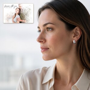 May include: A small silver hoop earring worn on an earlobe. In the upper left corner, a rectangular print displays a couple embracing with a watercolor effect and the text "forever with you" followed by the names "OLIVIA & ADAM".