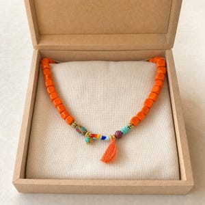 Orange and Red Statement Beaded Necklace worn with an ivory linen top in warm natural window light