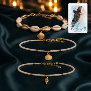 Beach Muse Three-Piece Shell Anklet Set arranged on soft ivory linen in a refined neutral flat lay.
