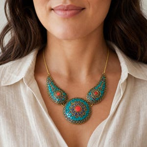 Turquoise and coral three medallion statement necklace with antique gold chain displayed on a jewelry bust with the layered beadwork and pendants visible