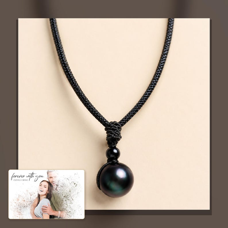 Black cord necklace with a dark round pendant, alternate framed view. A personalized greeting-card example appears in the corner.