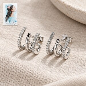 Triple Arc Stud Earrings, laid on fabric. A sample personalized digital greeting card is shown alongside.
