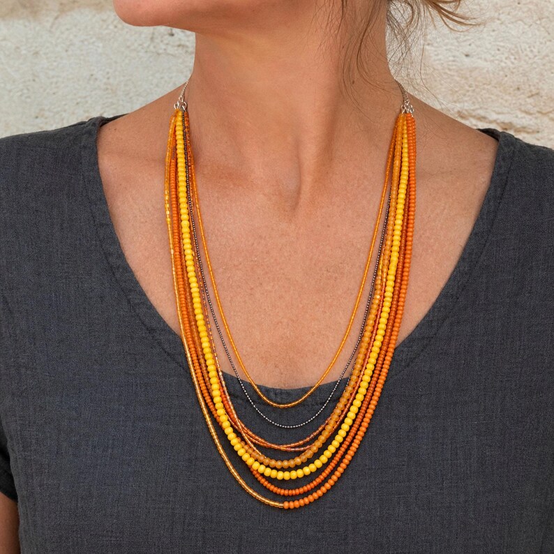 Three-piece handmade necklace set featuring orange and gray beaded necklace, gray and silver beaded necklace and rose gold and gray beaded necklace, displayed together to show the coordinated colors and beadwork