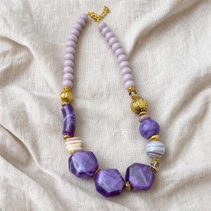 Purple and Lavender Statement Beaded Necklace presented in an open jewelry gift box on natural linen