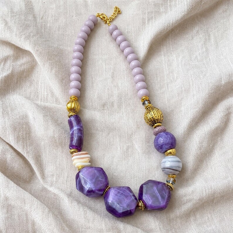 Purple and Lavender Statement Beaded Necklace presented in an open jewelry gift box on natural linen
