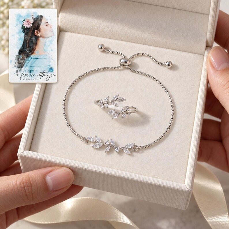 Adult hands passing an open ivory gift box containing the leaf bracelet and matching ring. A personalized digital greeting card is shown alongside.