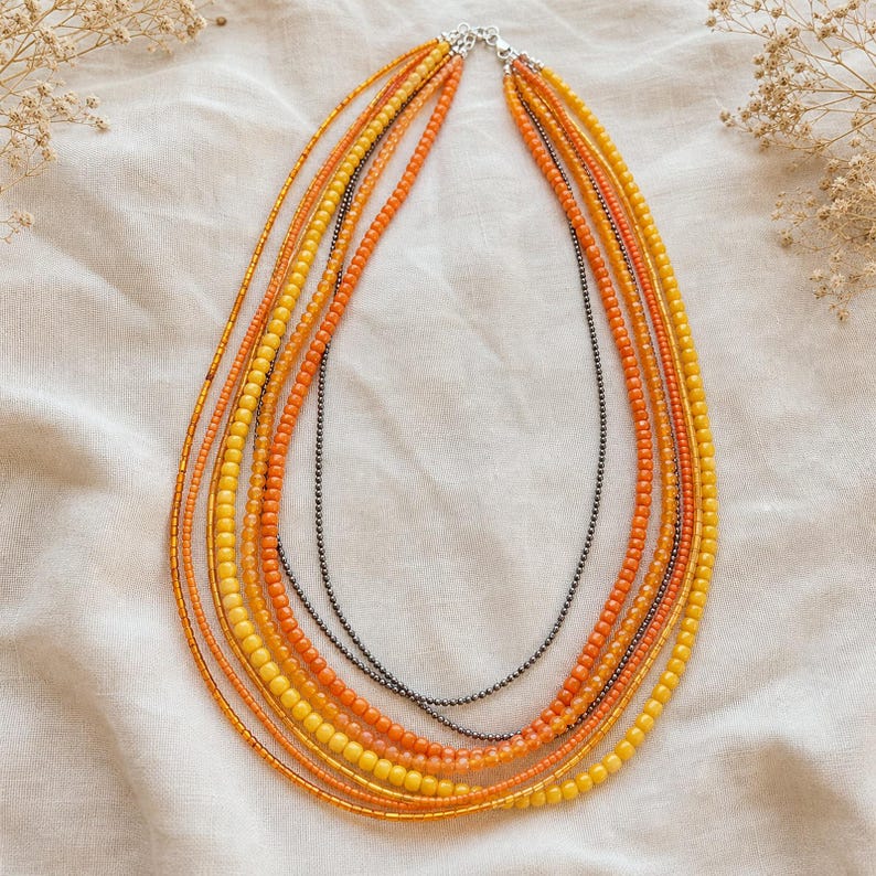 Gift ready presentation of Long multistrand orange amber yellow and gunmetal necklace in an open jewelry box lined with natural ivory linen