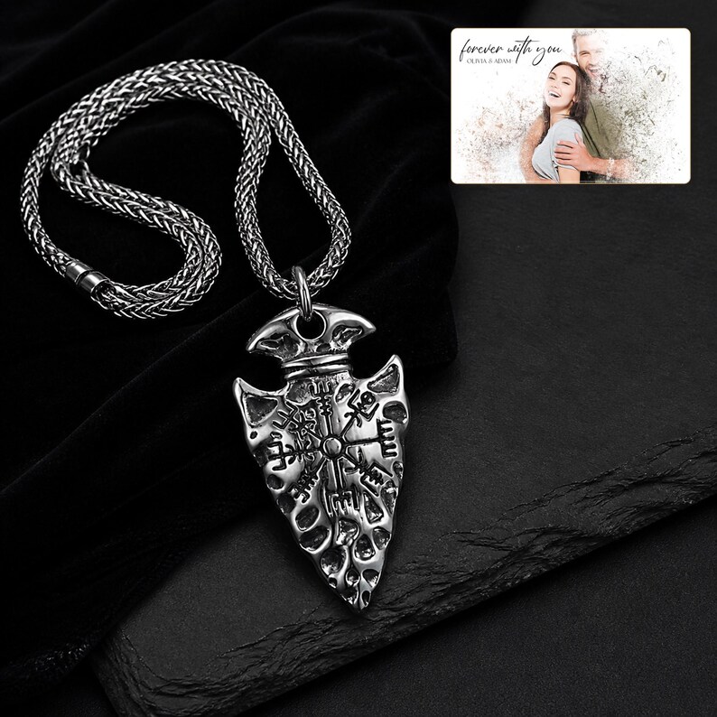 May include: A silver-toned arrowhead pendant featuring an engraved Vegvisir symbol on a thick woven chain. Included is a rectangular card displaying a photograph of a couple with the text "forever with you" and "OLIVIA & ADAM" printed at the top.