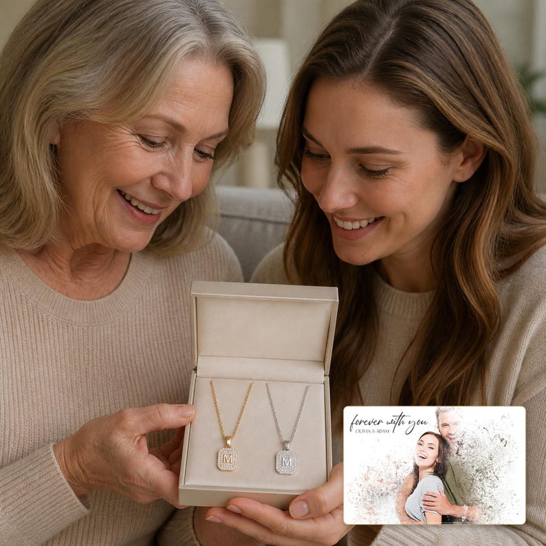 May include: A rectangular jewellery gift box containing two necklaces with rectangular pendants, each featuring the letter M. One necklace is gold-toned and the other is silver-toned, both with a textured border. A card with the text forever with you.