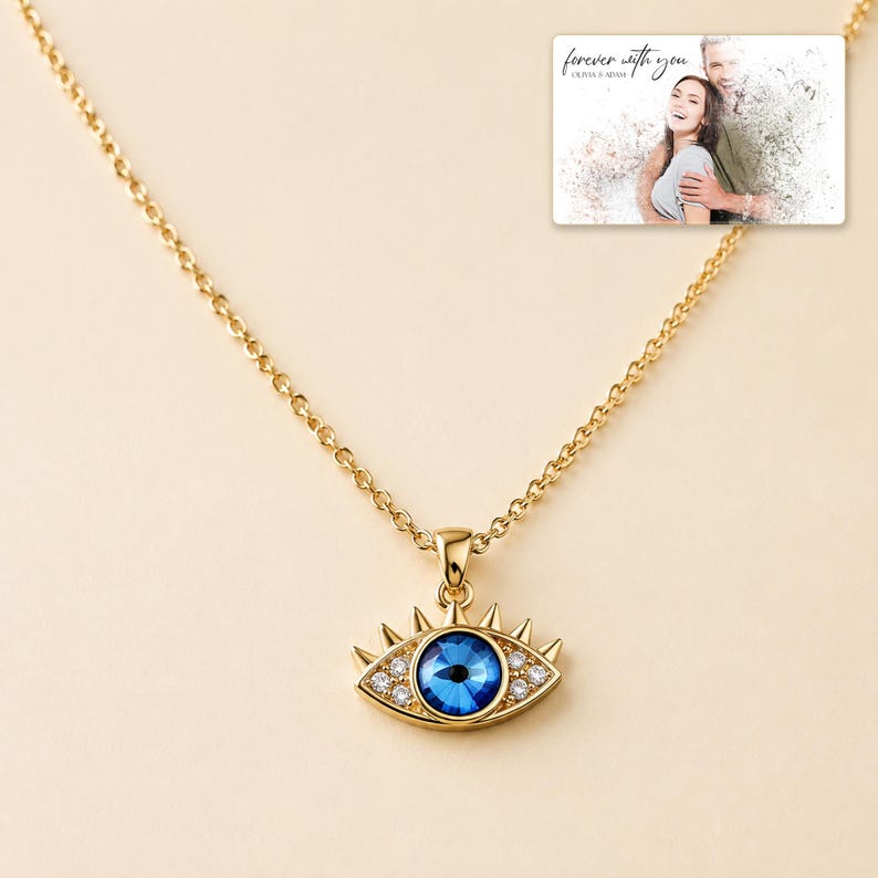 Gold-tone necklace with a blue eye-shaped pendant, display view. A personalized greeting-card example appears in the corner.
