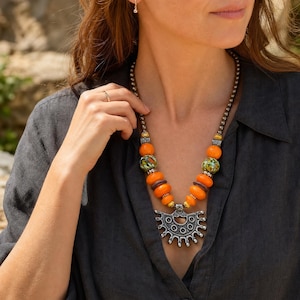Three-piece handmade necklace set featuring orange and brown beaded necklace, orange and brown beaded necklace and orange and brown beaded necklace, displayed together to show the coordinated colors and beadwork