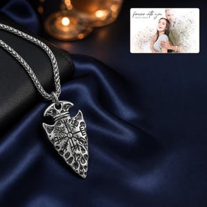 Aegis North Nordic Arrowhead Necklace arranged on soft ivory linen in a refined neutral flat lay.