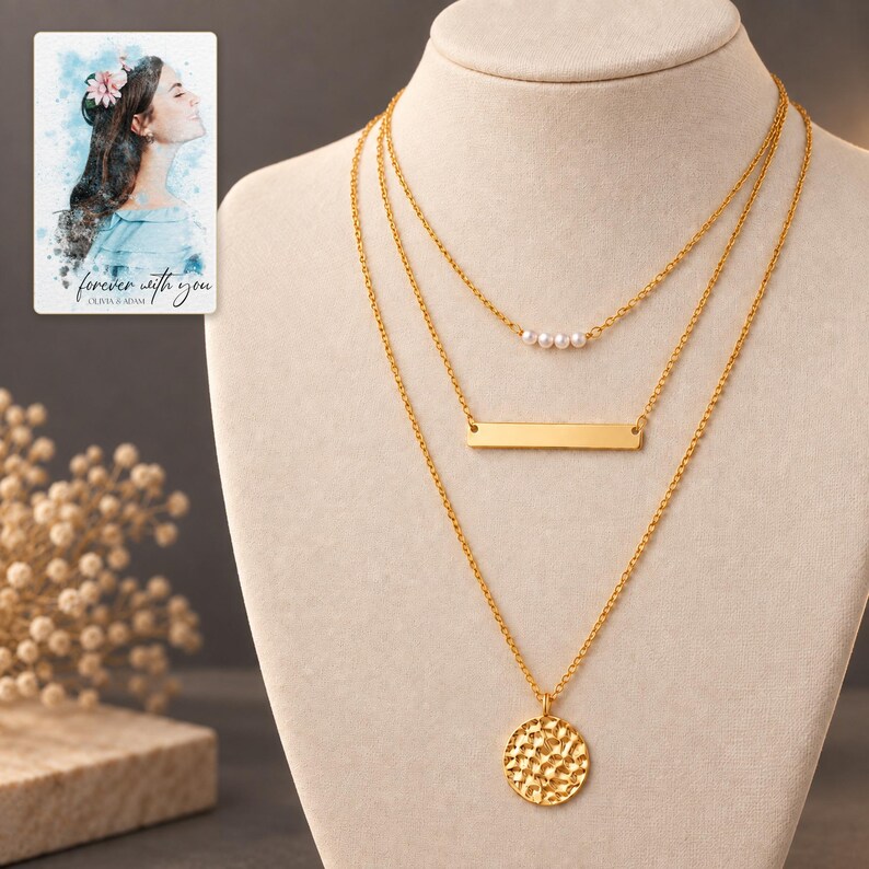 Gold-tone three-necklace set displayed against dark graphite, with four white pearl-style beads and a textured coin clearly visible. A personalized digital greeting card is shown alongside.
