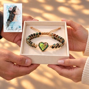 Verdant Heart Woven Bracelet shown during a warm gift-receiving moment between adults with the jewelry visible. A personalized digital greeting card is shown alongside.