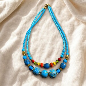 Blue and Clear Statement Beaded Necklace presented in an open jewelry gift box on natural linen