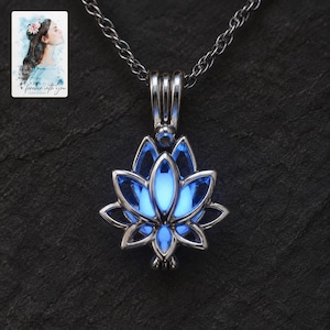 May include: A silver-toned metal pendant shaped like a lotus flower, featuring a glowing blue orb at its center. The pendant hangs from a matching silver-toned chain. A small card in the corner displays an illustration of a person with the text "forever with you".