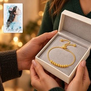 Golden Spiral Bead Slider Bracelet shown during a warm gift-receiving moment between adults with the jewelry visible. A personalized digital greeting card is shown alongside.