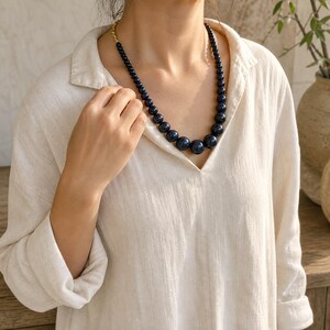 Gray and Bronze Statement Beaded Necklace displayed on a jewelry bust, showing the necklace shape and artisan bead details