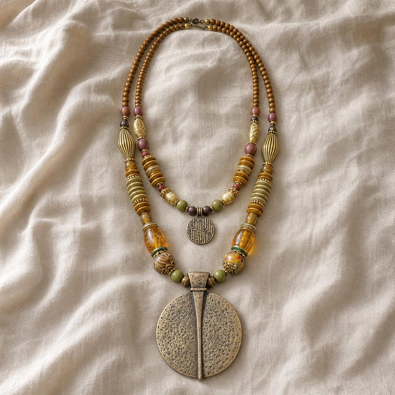 Gift ready presentation of Two-tier bronze, amber and olive beaded statement necklace with layered round pendants in an open jewelry box lined with natural ivory linen