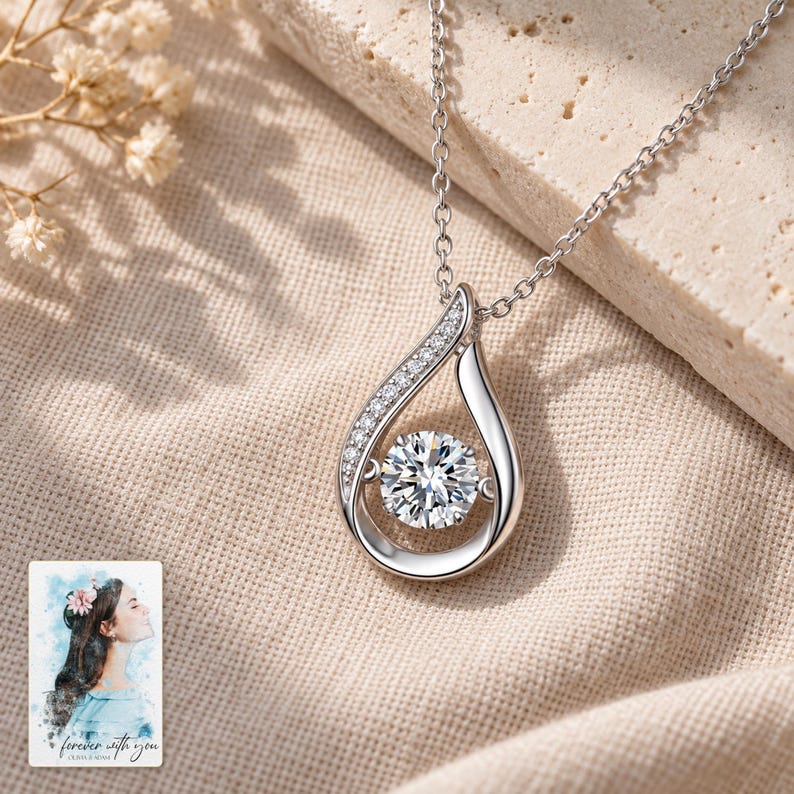 Moissanite Teardrop Necklace, laid on fabric. A sample personalized digital greeting card is shown alongside.
