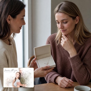 May include: A silver necklace with a delicate chain and a small, open-heart pendant presented in a white, hinged jewelry box. A rectangular card is displayed in the foreground featuring a printed photograph of a couple with the text forever with you.