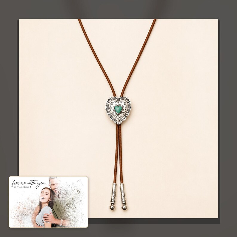 Brown cord bolo necklace with a silver-tone heart slide and turquoise-color center, dark-bordered product view. A personalized greeting-card example appears in the corner.
