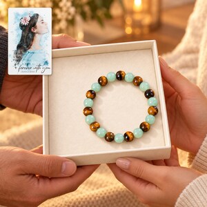 Forest Amber Bead Bracelet shown during a warm gift-receiving moment between adults with the jewelry visible. A personalized digital greeting card is shown alongside.