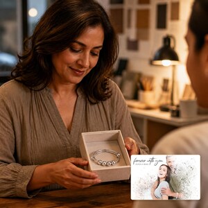 May include: A silver-toned bangle bracelet featuring four small, smooth, spherical beads along the band, presented inside a light-colored, square-shaped gift box. A rectangular card accompanies the box, displaying the text "forever with you" and "OLIVA & ADAM" above a faded, artistic photograph of a couple.