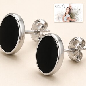 Black oval stud earrings with silver-tone edges, close detail view. A personalized greeting-card example appears in the corner.