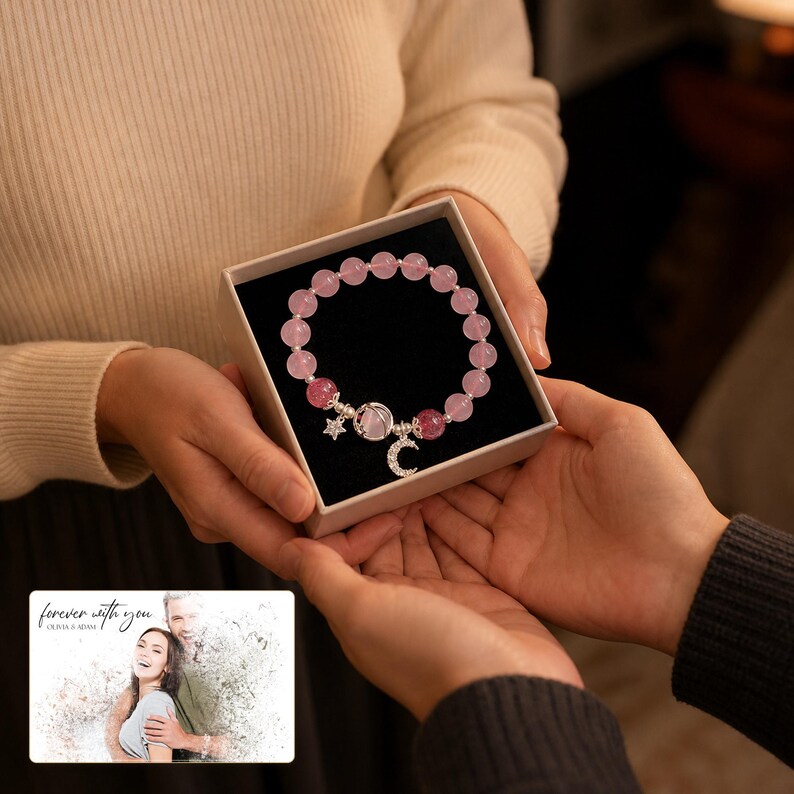Puede incluir: Una pulsera de cuentas con esferas transl&uacute;cidas en rosa claro y oscuro, un dije de media luna plateado, una estrella peque&ntilde;a y un dije redondo, presentada en una caja cuadrada con interior negro y una tarjeta con el texto "forever with you" y "OLIVIA & ADAM".