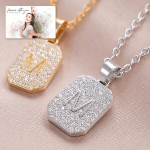 Mosaic Initial M Necklace Duo shown during a warm gift-receiving moment between adults with the exact jewelry visible.